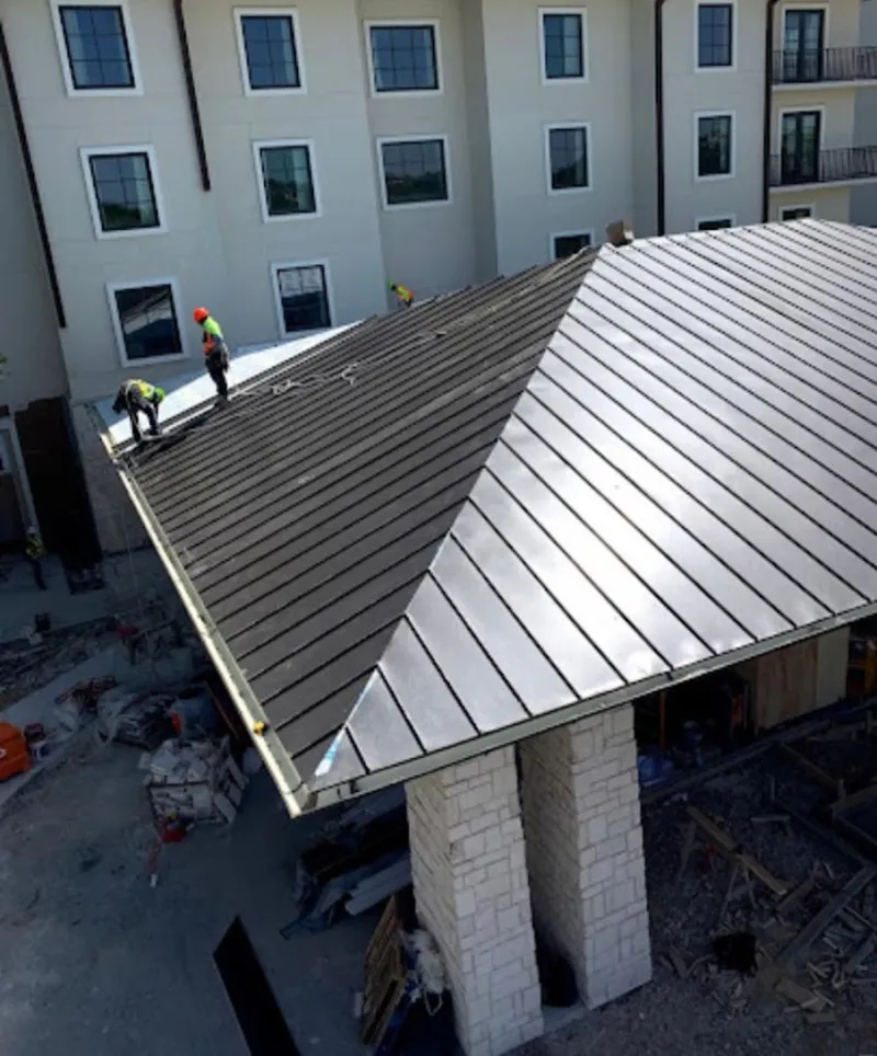 Crew installing standing seam metal roof panels on a commercial project in Pelican Bay